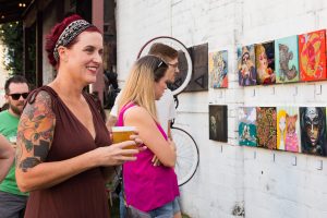 Woman with Red hair and beer Enjoying Art at Black Amethyst Tattoo Gallery Art Show
